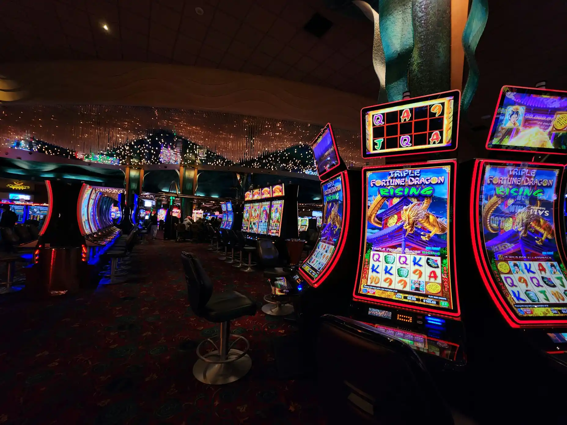 Rekke med fargerike spilleautomater i et fysisk casino