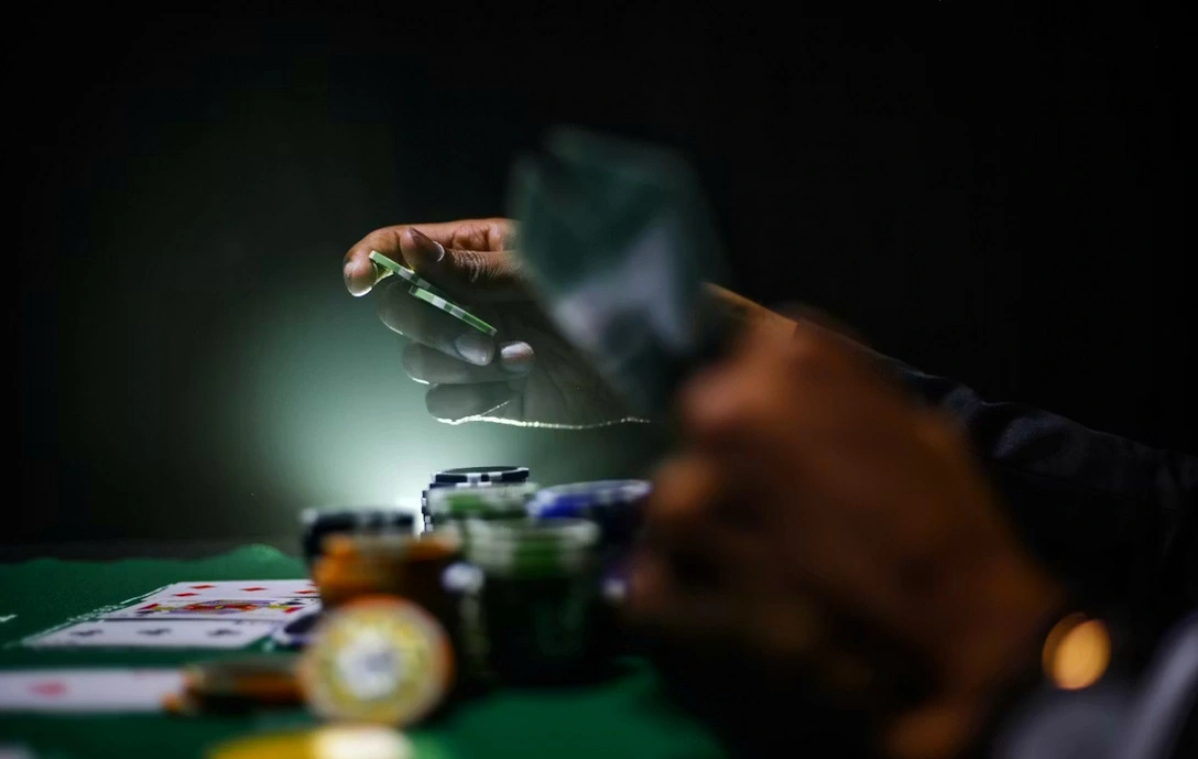 Spiller ved et mørkt pokerbord med casinochips