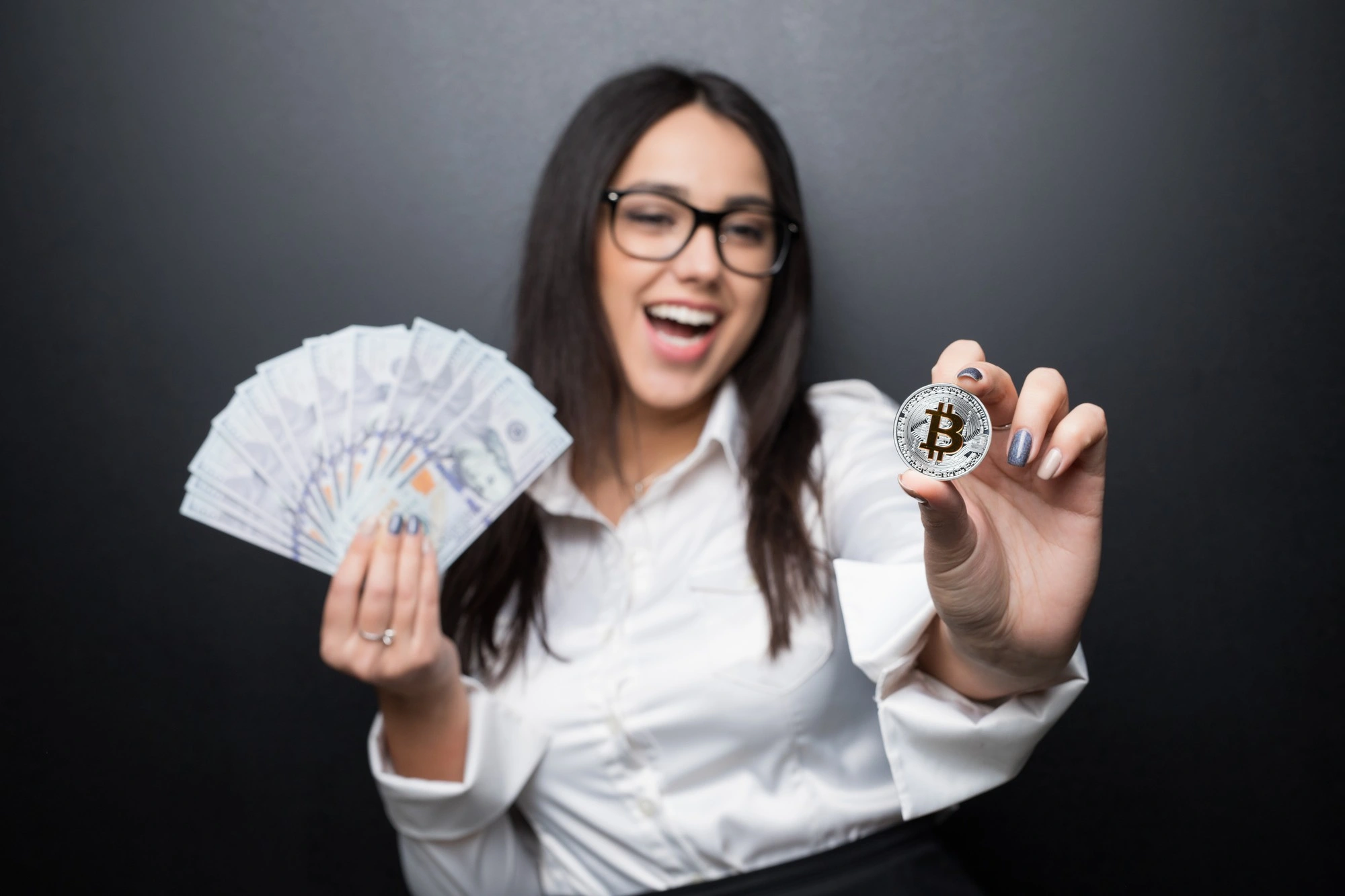 Glad kvinne som viser frem kontanter og en bitcoin